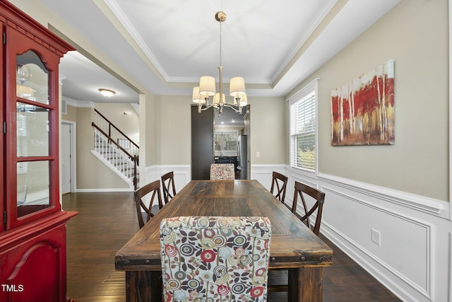 dining room with an inviting chandelier, dark hardwood / wood-style floors, a raised ceiling, and crown molding