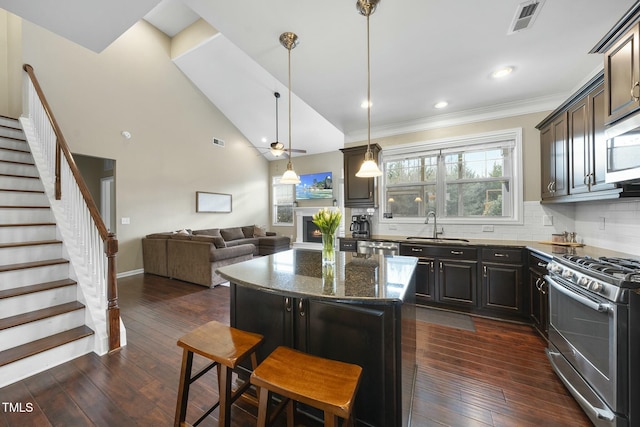 kitchen with a kitchen island, dark hardwood / wood-style flooring, a kitchen bar, dark stone counters, and stainless steel appliances