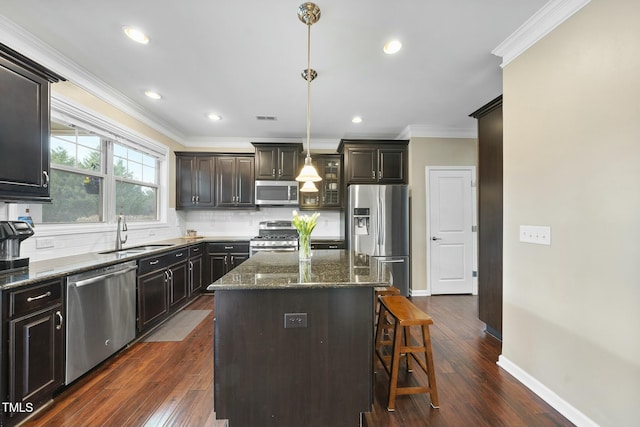 kitchen featuring pendant lighting, sink, backsplash, stainless steel appliances, and a kitchen island