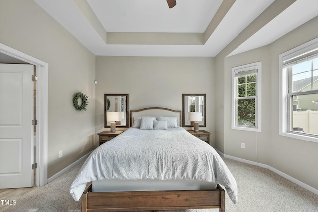 carpeted bedroom featuring a raised ceiling and ceiling fan