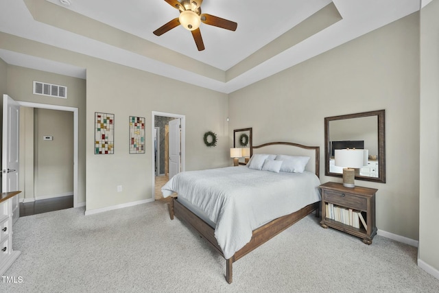 bedroom with light carpet, a tray ceiling, and ceiling fan