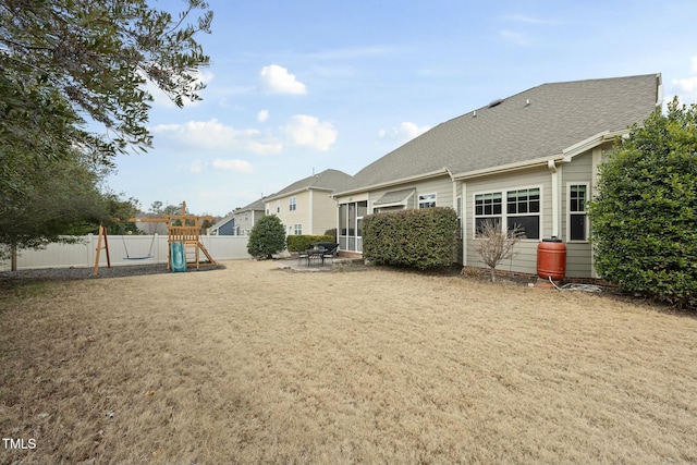 back of property featuring a playground and a yard