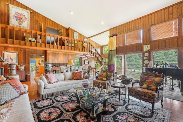 living room with high vaulted ceiling, wood-type flooring, and wooden walls