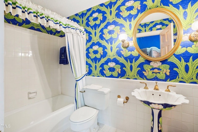 bathroom featuring toilet, shower / bath combination with curtain, and tile walls