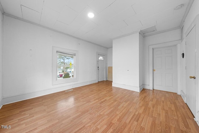 empty room with ornamental molding and light wood-type flooring