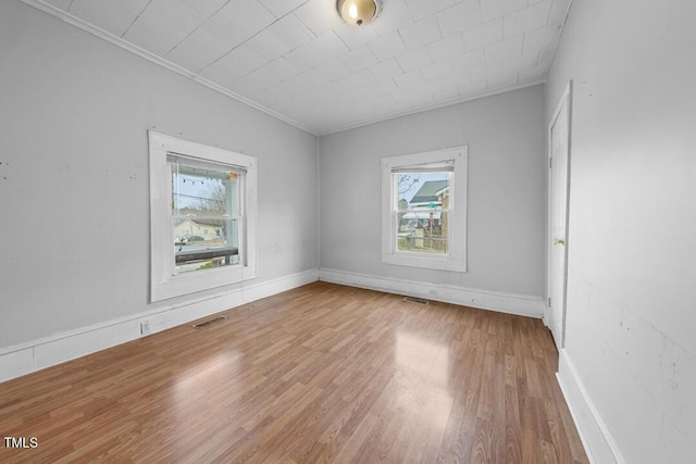 spare room with ornamental molding, plenty of natural light, and wood-type flooring