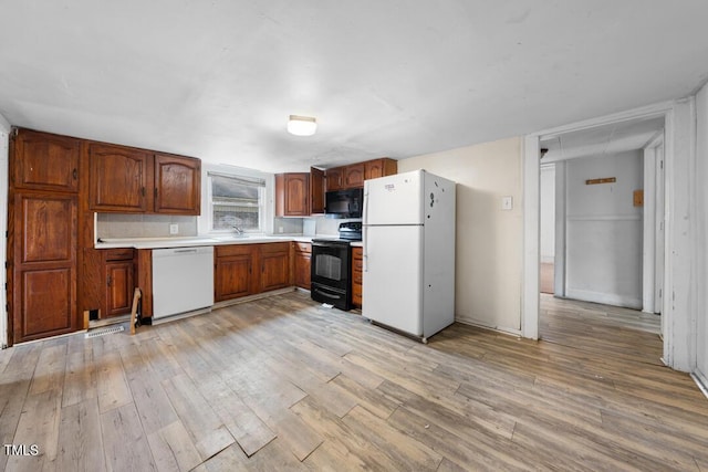 kitchen with sink, light hardwood / wood-style floors, and black appliances