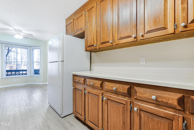 kitchen with white refrigerator, ceiling fan, light wood-type flooring, and a textured ceiling