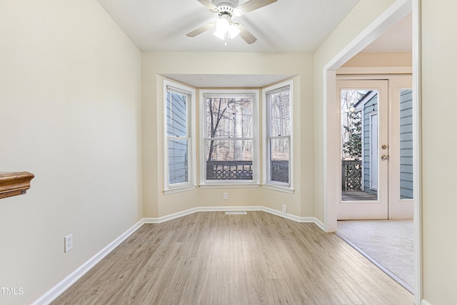 spare room with ceiling fan, light hardwood / wood-style flooring, and a textured ceiling