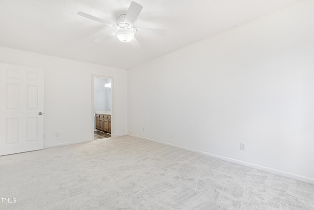 unfurnished bedroom with ceiling fan, ensuite bath, and light carpet