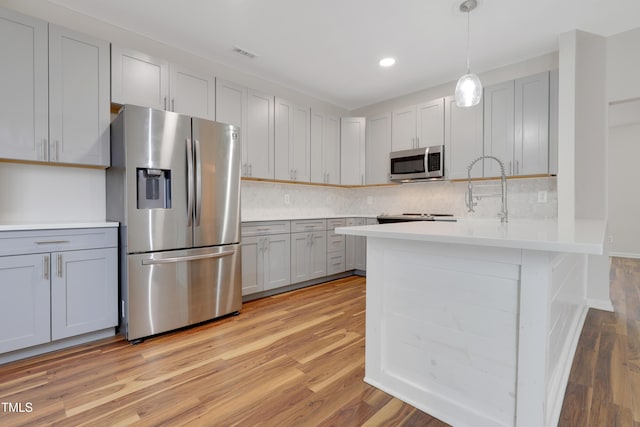 kitchen with sink, light hardwood / wood-style flooring, gray cabinets, appliances with stainless steel finishes, and hanging light fixtures