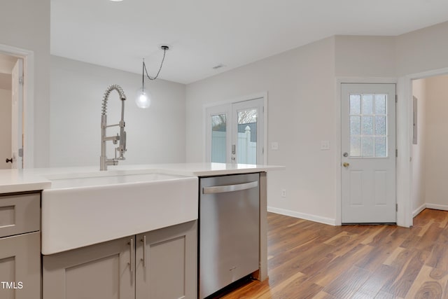 kitchen with hanging light fixtures, plenty of natural light, sink, and stainless steel dishwasher