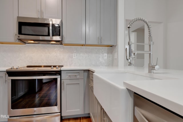 kitchen with stainless steel appliances, tasteful backsplash, sink, and gray cabinets