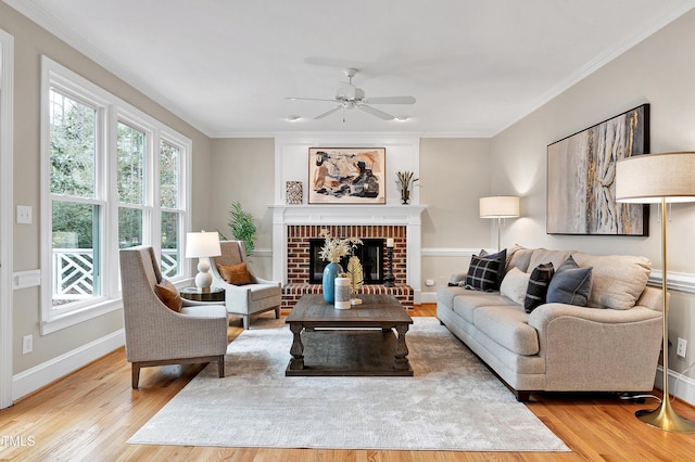 living room featuring a brick fireplace, crown molding, wood-type flooring, and ceiling fan