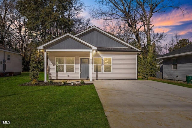 view of front of home with cooling unit, a porch, and a lawn