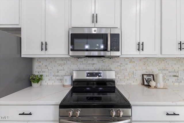 kitchen with stainless steel appliances, white cabinetry, and light stone countertops