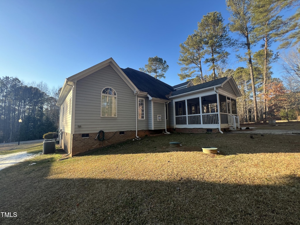 view of front of house featuring a front yard, a sunroom, and central air condition unit