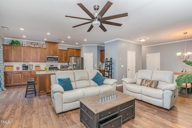 living room featuring crown molding, wood-type flooring, and ceiling fan with notable chandelier