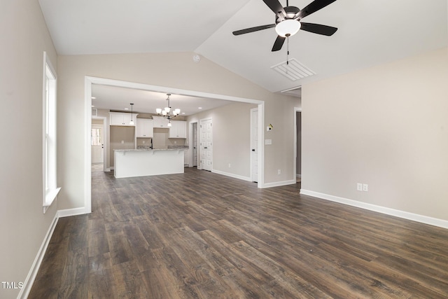 unfurnished living room featuring dark wood-type flooring, ceiling fan with notable chandelier, and vaulted ceiling