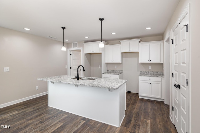 kitchen featuring light stone counters, sink, white cabinetry, and a kitchen island with sink