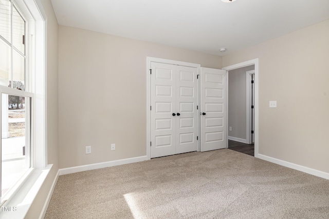 unfurnished bedroom with multiple windows, carpet floors, and a closet