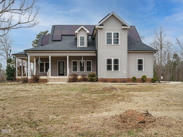 view of front of house featuring a porch, a front yard, and solar panels