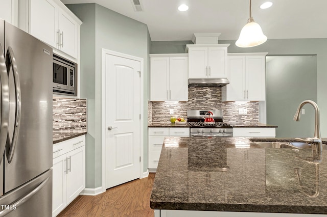 kitchen with appliances with stainless steel finishes, decorative light fixtures, sink, dark stone countertops, and white cabinets