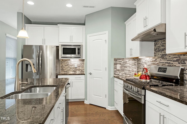 kitchen with sink, hanging light fixtures, stainless steel appliances, and dark stone counters