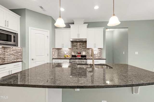 kitchen featuring stainless steel appliances, dark stone countertops, sink, and pendant lighting