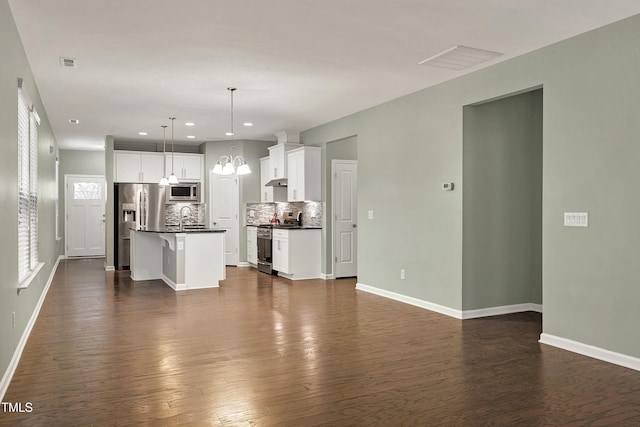 unfurnished living room featuring an inviting chandelier, dark hardwood / wood-style flooring, and sink