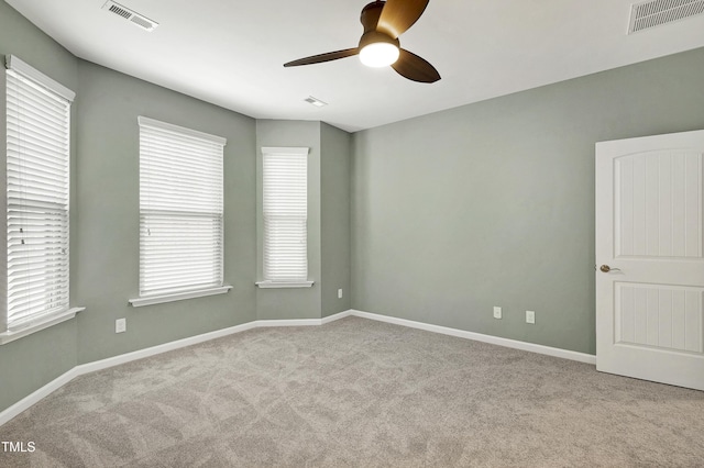 carpeted empty room with ceiling fan and plenty of natural light