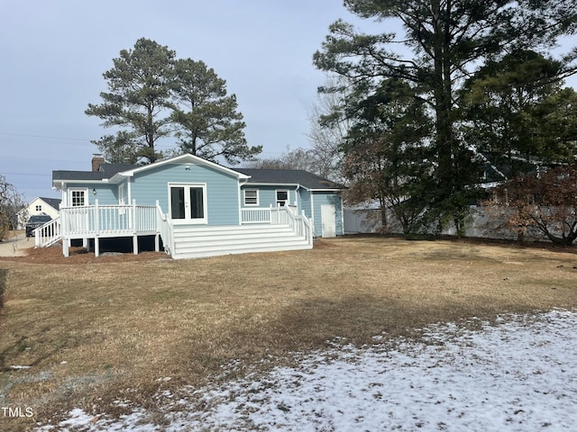 snow covered house with a wooden deck and a yard