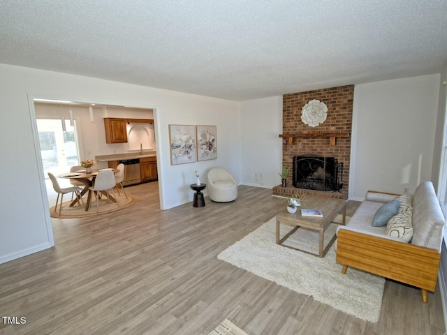 living room with a brick fireplace, a textured ceiling, and light wood-type flooring