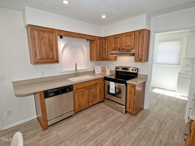 kitchen featuring sink, light hardwood / wood-style flooring, stainless steel appliances, and a textured ceiling