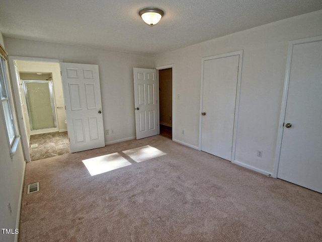 unfurnished bedroom with light colored carpet and a textured ceiling