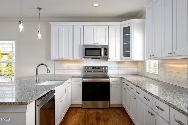 kitchen featuring decorative light fixtures, appliances with stainless steel finishes, glass insert cabinets, ornamental molding, and white cabinetry