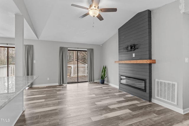 unfurnished living room with ceiling fan, light hardwood / wood-style flooring, lofted ceiling, and a fireplace