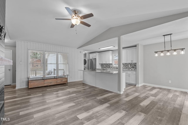 kitchen with white cabinetry, backsplash, hanging light fixtures, stainless steel refrigerator, and light wood-type flooring