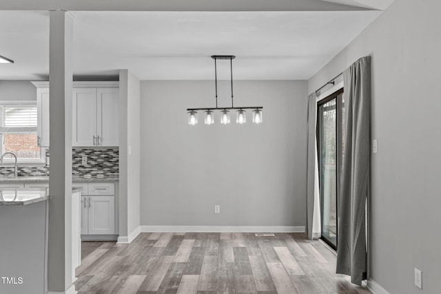 unfurnished dining area with sink and light wood-type flooring