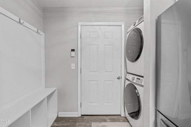 clothes washing area with wood-type flooring and stacked washer and dryer