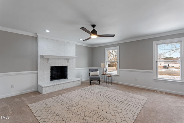 living area with ceiling fan, light colored carpet, ornamental molding, and a fireplace