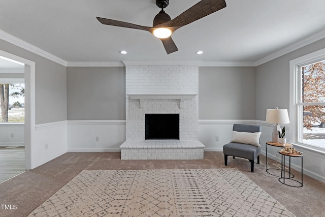 living area featuring crown molding, light carpet, ceiling fan, and a fireplace