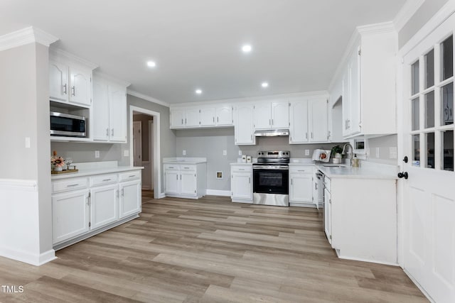 kitchen with appliances with stainless steel finishes, sink, white cabinets, and light hardwood / wood-style flooring