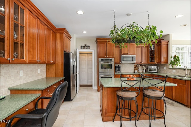 kitchen with a kitchen bar, sink, stone countertops, a kitchen island, and stainless steel appliances