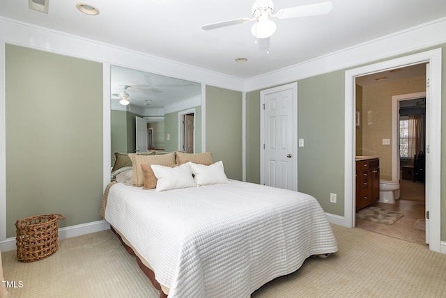 bedroom with ceiling fan, light colored carpet, ensuite bathroom, and ornamental molding