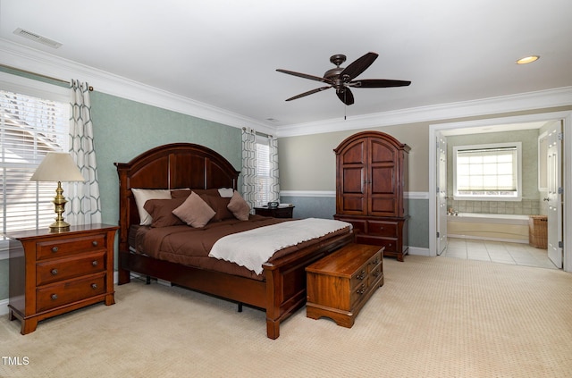 carpeted bedroom with ensuite bath, ornamental molding, and ceiling fan