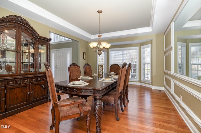 dining space featuring a tray ceiling, a chandelier, and light wood-type flooring