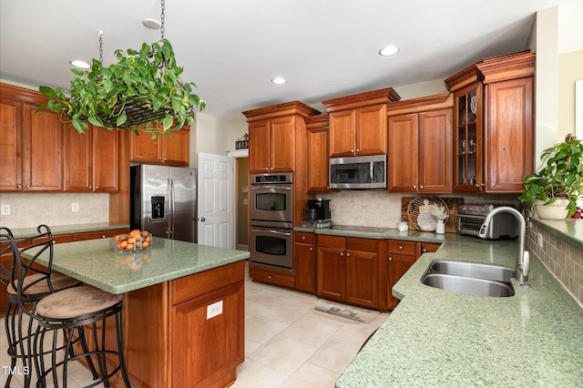 kitchen with appliances with stainless steel finishes, a breakfast bar, sink, and decorative backsplash