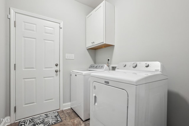 washroom with separate washer and dryer, dark tile patterned flooring, and cabinets