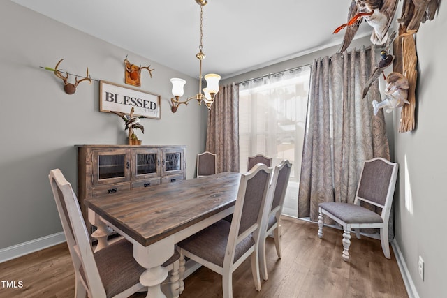 dining space with dark wood-type flooring and an inviting chandelier